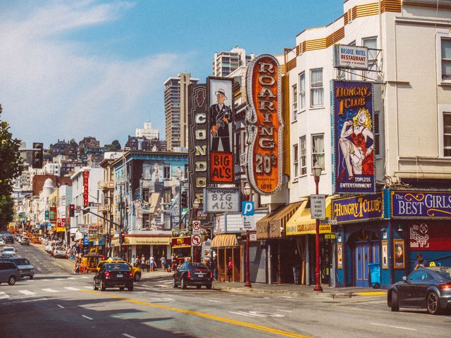 Straat met opvallende neon uithangborden van clubs en bars, auto's en voetgangers in de wijk North Beach in San Francisco