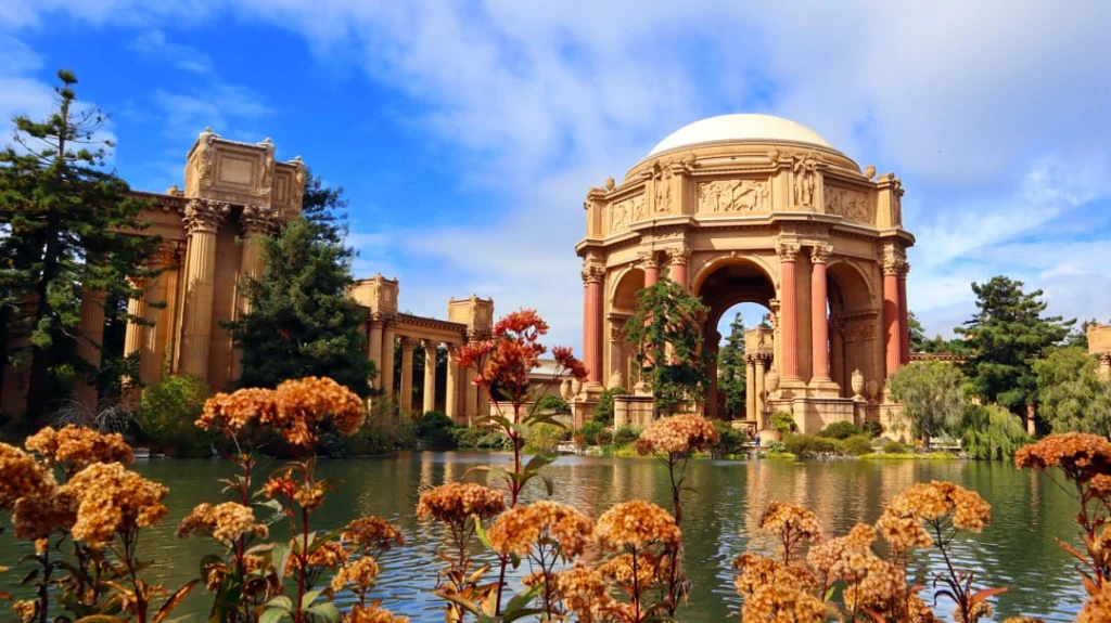 Klassieke koepel en zuilen van het Palace of Fine Arts weerspiegeld in een vijver met bloemen op de voorgrond