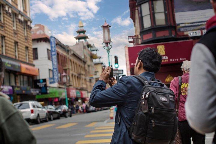 Man met rugzak maakt een foto van een pagode in een drukke winkelstraat in Chinatown in San Francisco