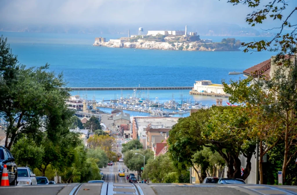 Vanaf een steile straat in San Francisco kijk je over de haven uit naar het eiland Alcatraz in de baai
