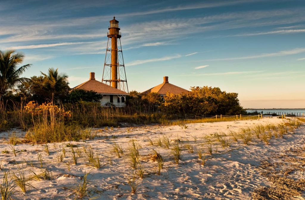 IJzeren vuurtoren op palen naast houten gebouwen met duinbegroeiing op de voorgrond op Sanibel Island