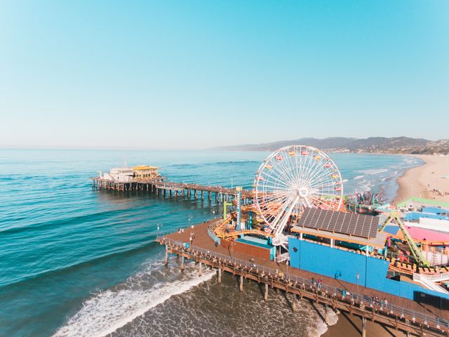 Luchtfoto van de pier van Santa Monica met een kleurrijk reuzenrad, een zandstrand en de oceaan op de achtergrond