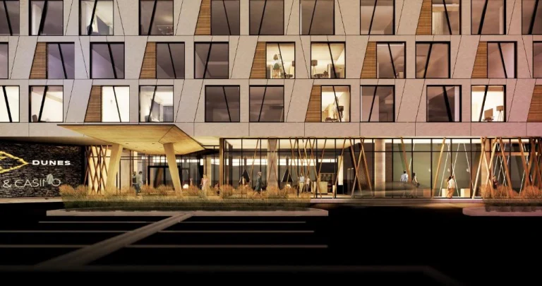 Modern hotel en casinogebouw in Saskatchewan bij avond met een groot bord met de tekst Dunes and Casino en verlichte raampartijen