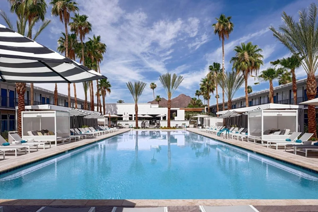 Rechthoekig zwembad omringd door palmbomen en gestreepte parasols met een piekvormige bergtop op de achtergrond in Scottsdale