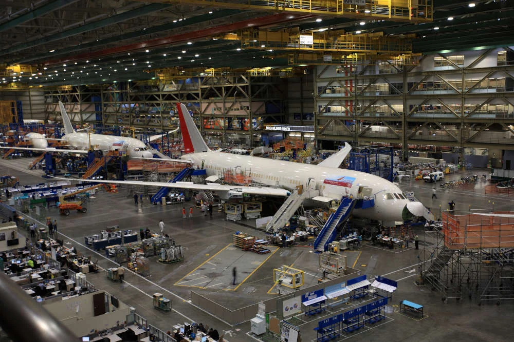 Grote fabriekshal met meerdere passagiersvliegtuigen in aanbouw, steigers en werknemers tussen het productiemateriaal bij Boeing in de buurt van Seattle