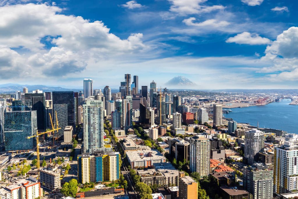Luchtfoto van de wolkenkrabbers van Seattle onder een blauwe lucht met wolken en de besneeuwde top van Mount Rainier in de verte