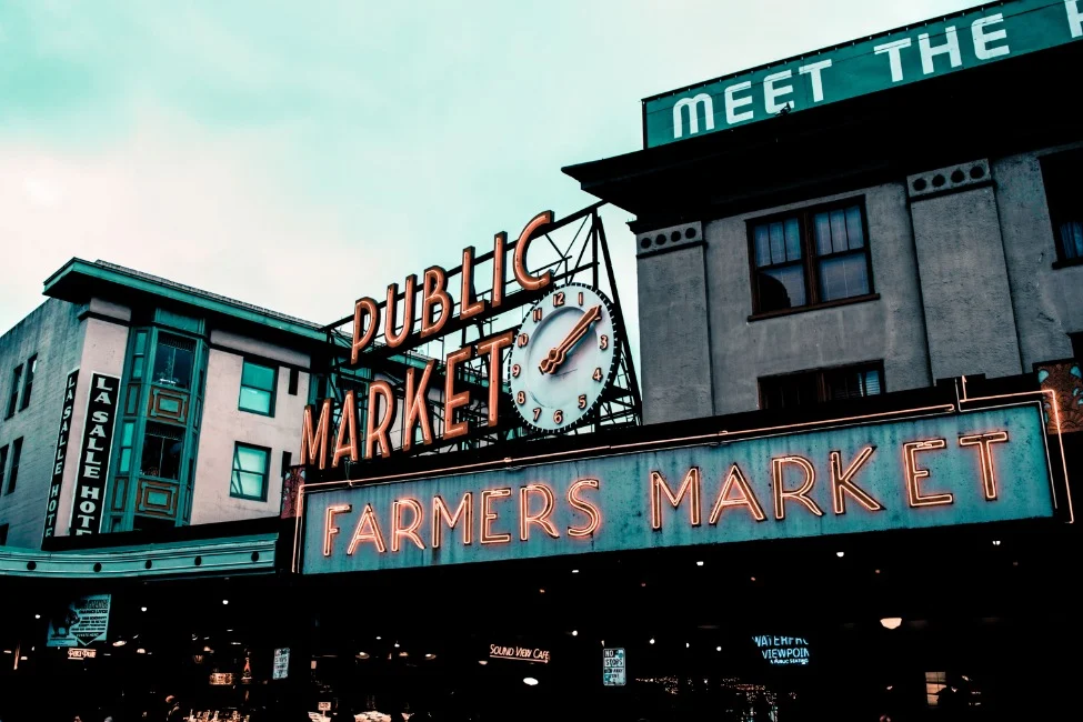 Groen en oranje neonbord met de tekst Public Market en Farmers Market boven de ingang van Pike Place Market in Seattle