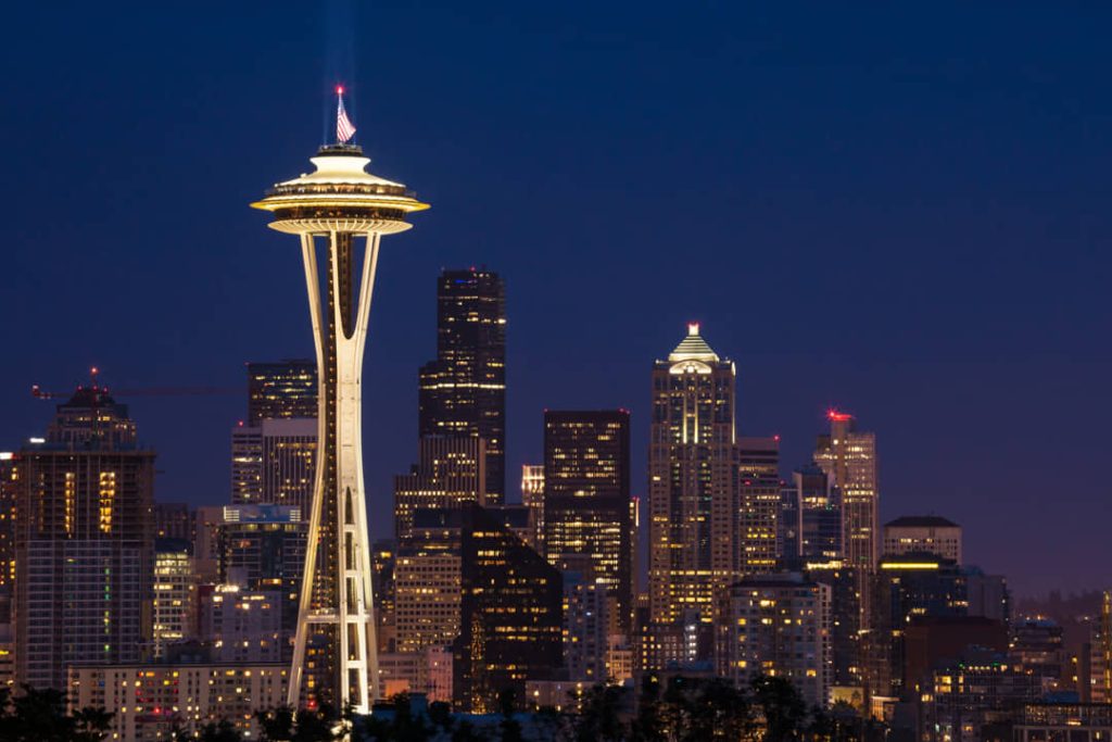 De verlichte Space Needle steekt uit boven de skyline van Seattle tijdens het blauwe uur in de avond