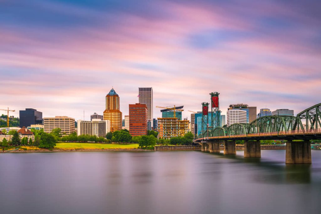 De skyline van Portland, Oregon met de Hawthorne Bridge over de Willamette rivier bij zonsondergang