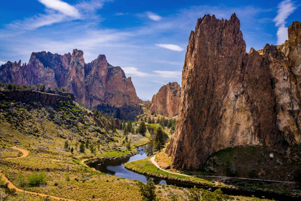 Steile rotspieken van Smith Rock State Park boven een kronkelende rivier onder een felle oranje avondlucht