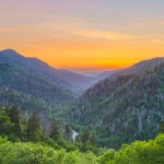 Weids uitzicht over beboste bergtoppen van de Smoky Mountains, met een gloeiende oranje lucht in de vallei