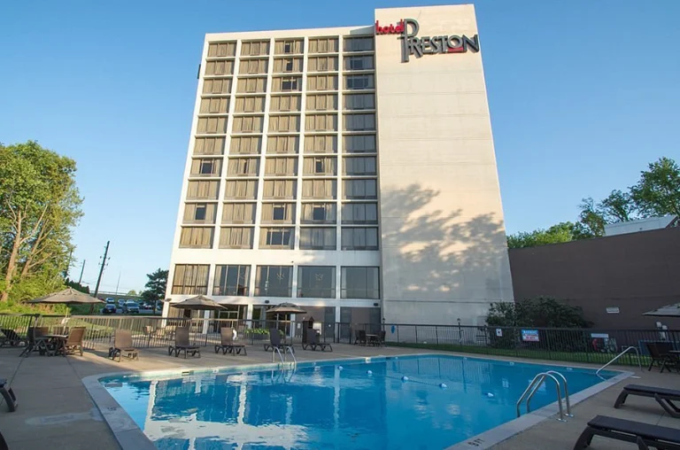 Hoog torengebouw van Hotel Preston in South Carolina met een groot buitenzwembad en ligstoelen op de voorgrond