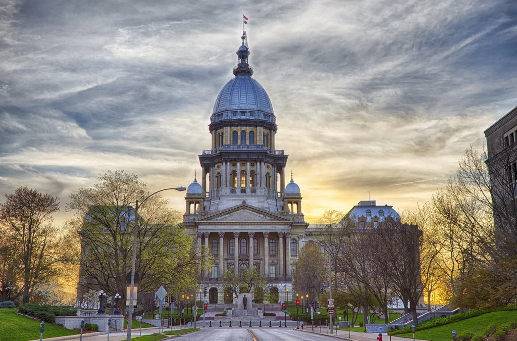 Het koepelgebouw van het Illinois State Capitol in Springfield gezien vanaf een brede laan bij een kleurrijke zonsondergang