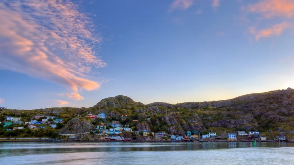 Uitzicht over het water op de kleurrijke huizen tegen de rotsachtige heuvels van St. John's in Newfoundland bij zonsondergang