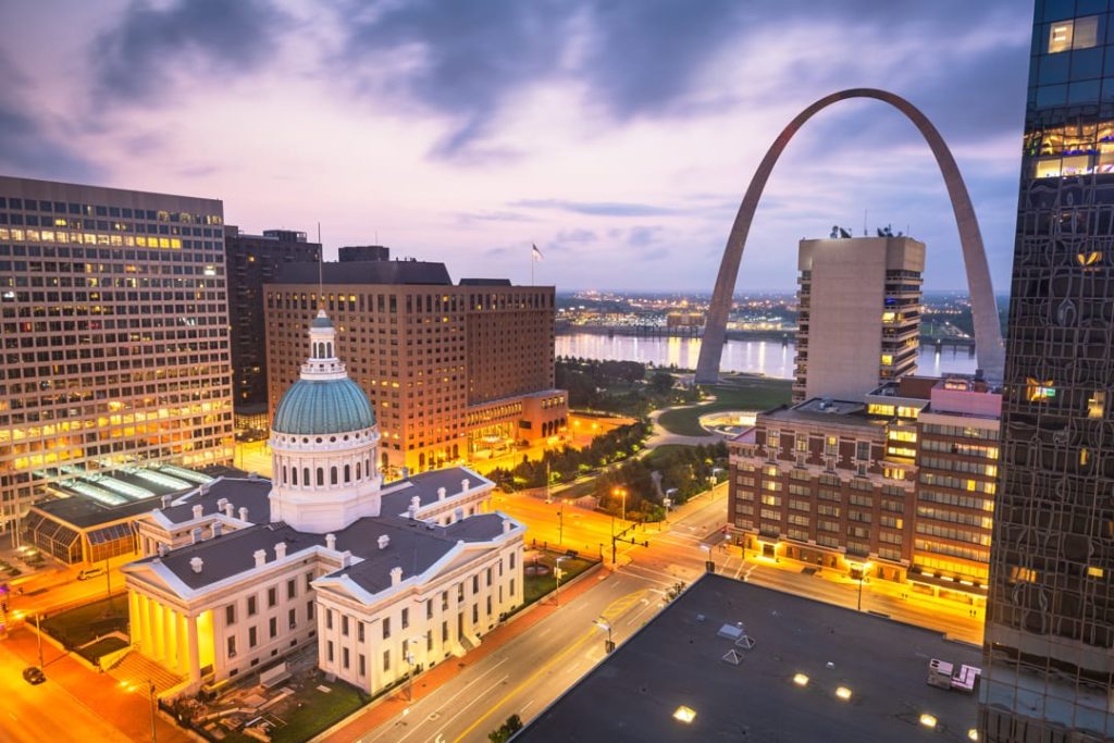 Luchtfoto over het historische gerechtsgebouw met koepel en de Gateway Arch, met verlichte gebouwen van St. Louis bij het vallen van de avond