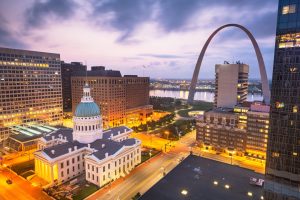 Luchtfoto over het historische gerechtsgebouw met koepel en de Gateway Arch, met verlichte gebouwen van St. Louis bij het vallen van de avond
