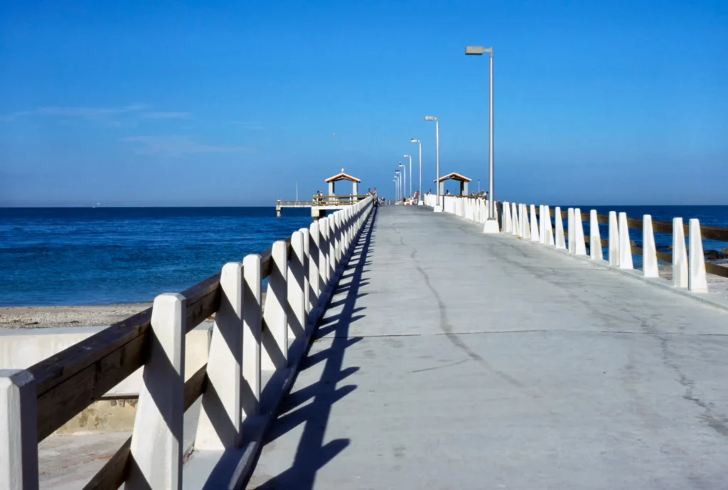 Lange betonnen vissteiger met witte reling loopt de zee in in Fort DeSoto Park bij St. Petersburg