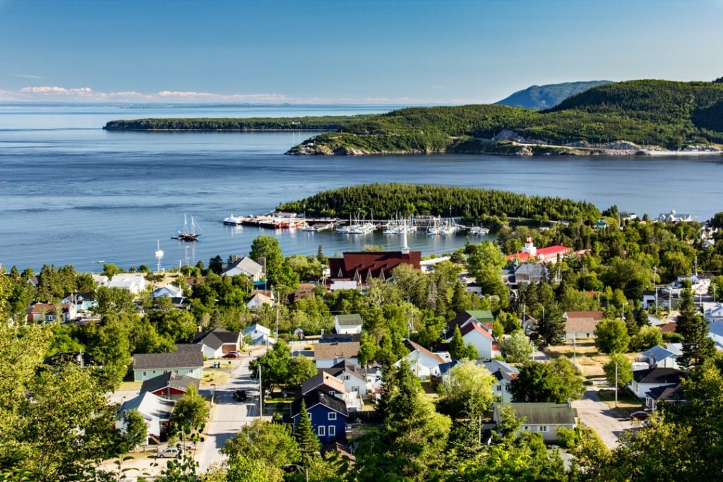 Luchtfoto van het dorp Tadoussac met bootjes in de jachthaven en huizen aan de oever van de rivier