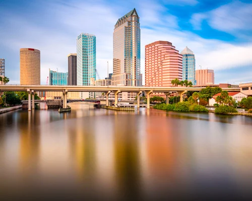 Verlichte wolkenkrabbers van Tampa weerspiegelen in het water van de rivier met een brug op de voorgrond