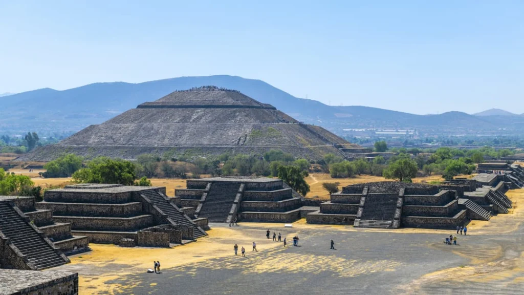 Uitzicht op de grote Piramide van de Zon in Teotihuacan met bergen op de achtergrond en bezoekers die de trappen beklimmen