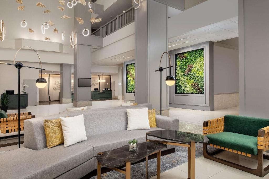 Moderne hotellobby met een grijze zithoek, hangende gouden decoraties en een verticale tuin met planten tegen de muur
