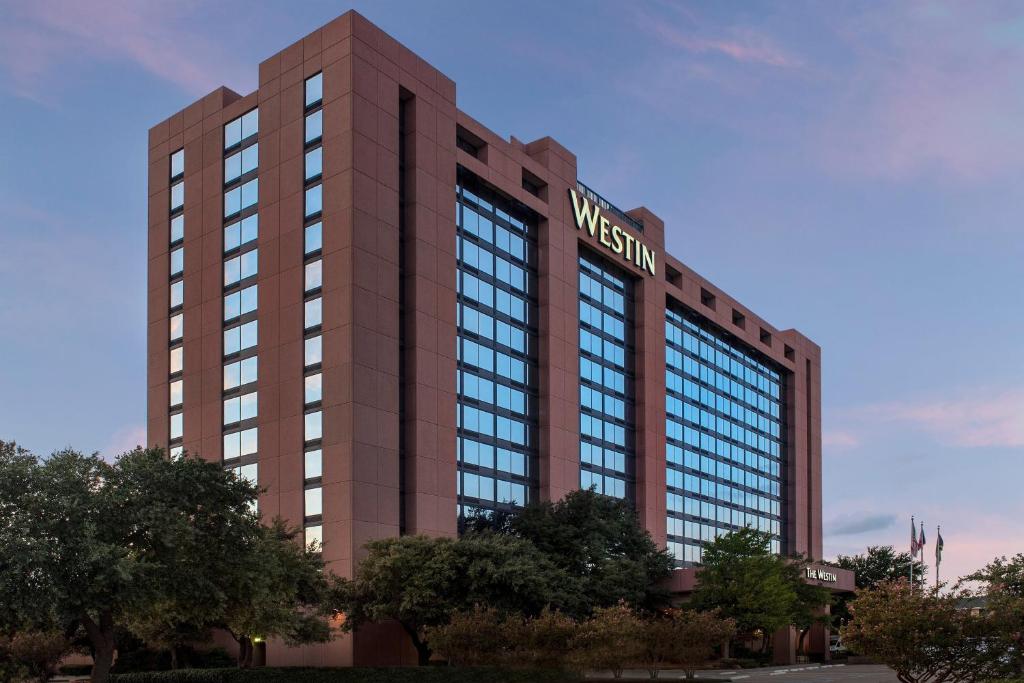 Hoog bruin hotelgebouw met de naam Westin in gouden letters op de gevel, gefotografeerd bij een roze avondlucht