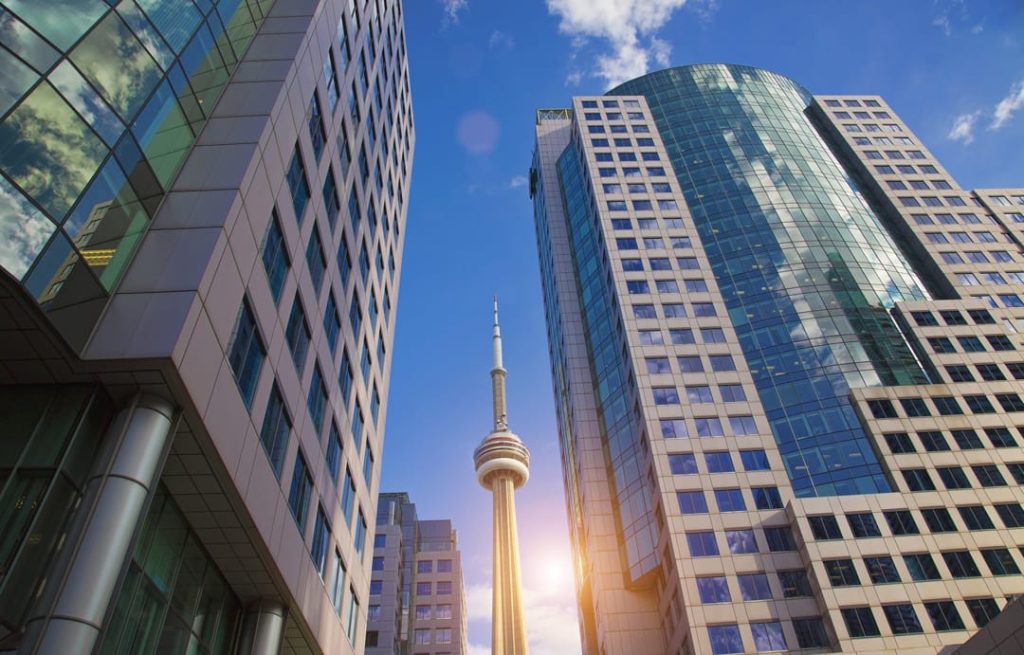 De spits van de CN Tower is zichtbaar tussen twee glazen kantoortorens in het centrum van Toronto
