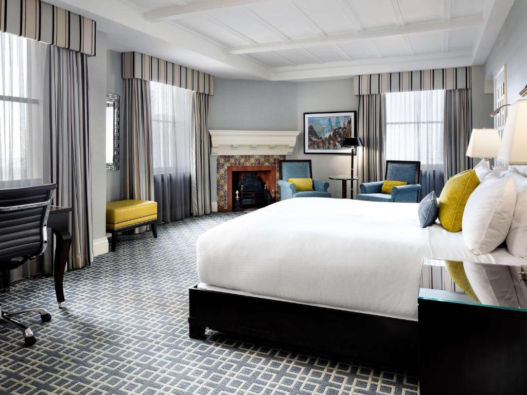 Ruime hotelkamer met een openhaard, gestreepte gordijnen en gele en blauwe accentkleuren in de zithoek