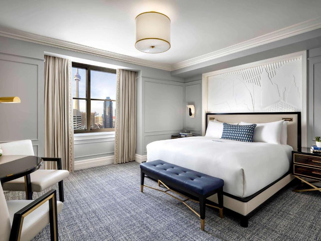 Hotelkamer met een groot bed en een raam met uitzicht op de CN Tower en de skyline van Toronto