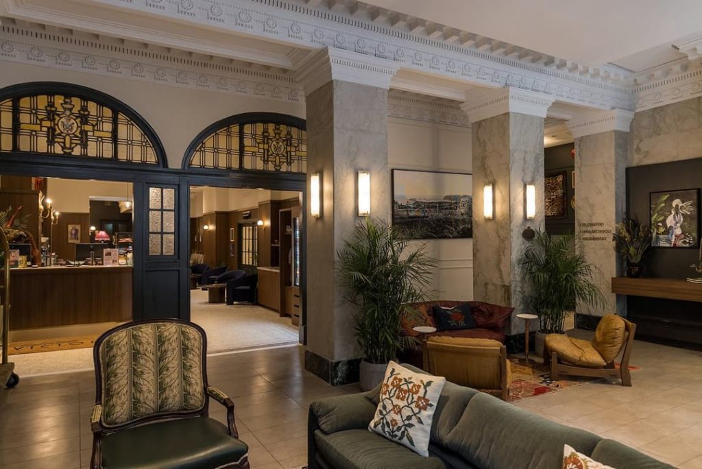 Een klassiek ingerichte hotellobby met marmeren zuilen, fauteuils en glas in loodramen bij Hotel Victoria in Toronto