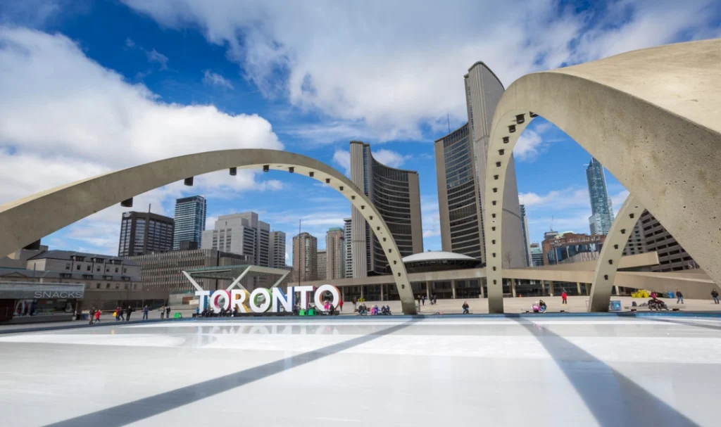 Toronto bord bij een ijsbaan op Nathan Phillips Square met de gebogen torens van het stadhuis en de skyline op de achtergrond