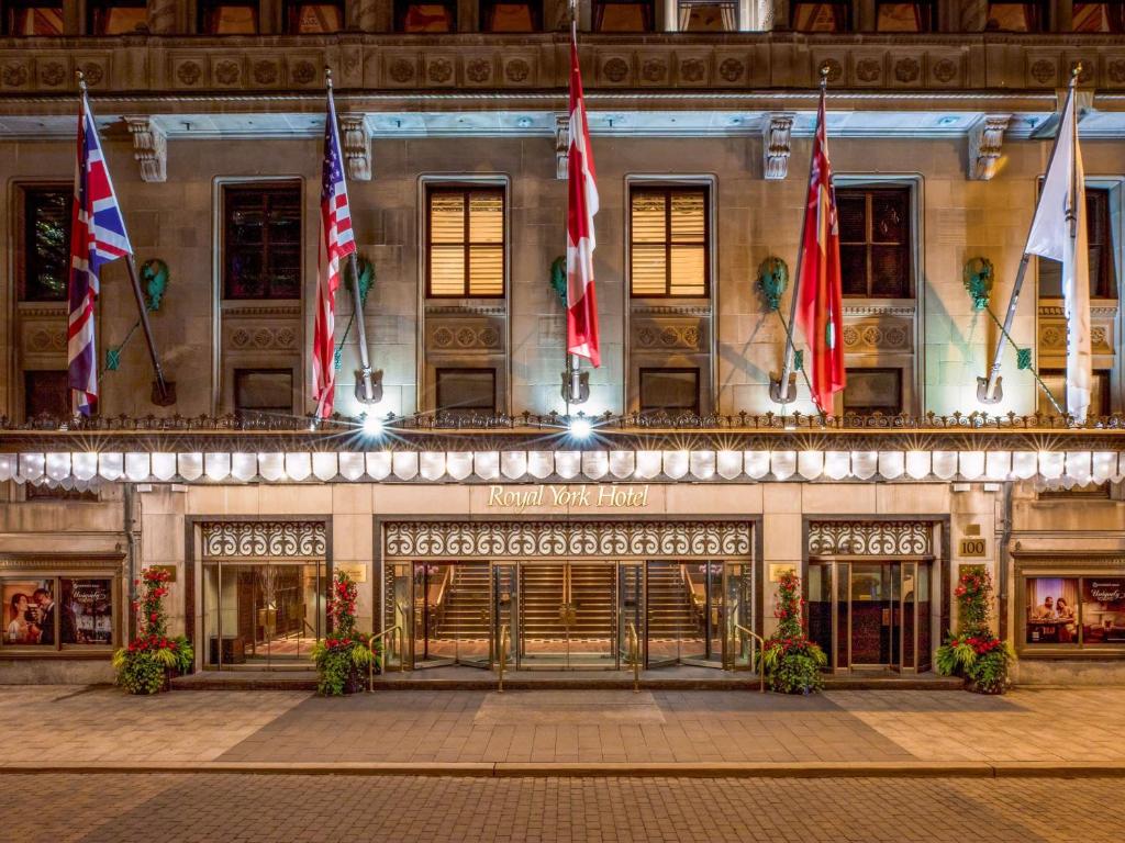Verlichte entree van een historisch hotel met internationale vlaggen aan gietijzeren masten en een luifel boven de deuren