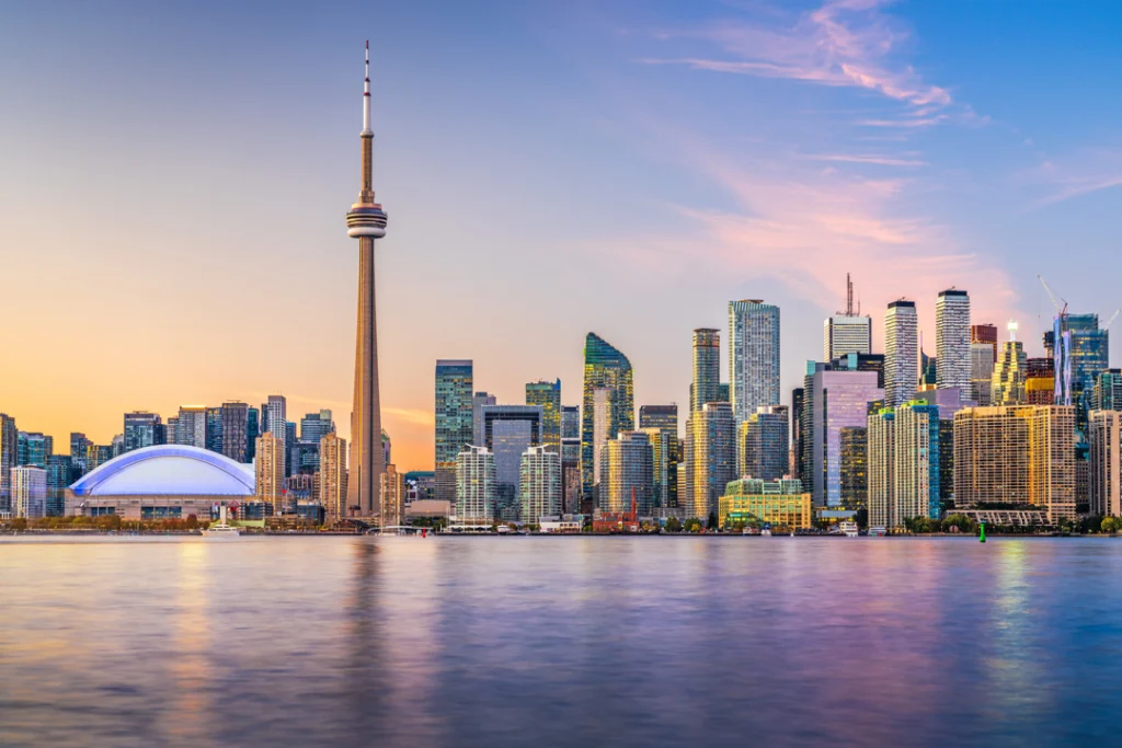 Skyline van Toronto met de CN Tower en wolkenkrabbers weerspiegeld in het water tijdens een roze gekleurde zonsondergang