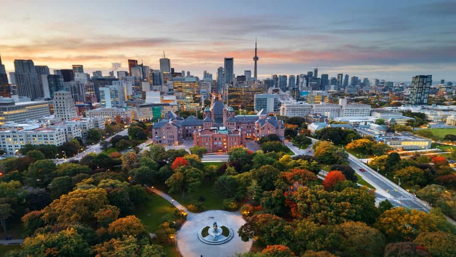 Luchtfoto van Toronto bij zonsondergang met de CN Tower en een park in herfstkleuren op de voorgrond