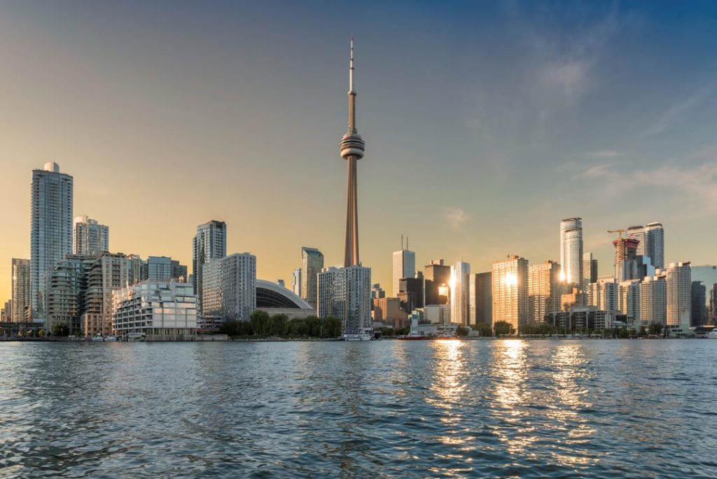De skyline van Toronto met de CN Tower weerspiegelt in het water van het meer bij een gouden zonsondergang