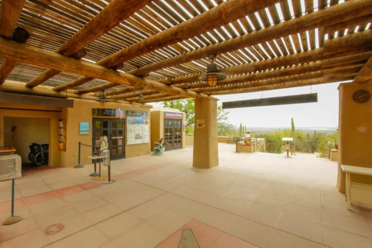 Bezoekerscentrum met een houten pergola en informatieborden bij de ingang van een natuurmuseum nabij Tucson