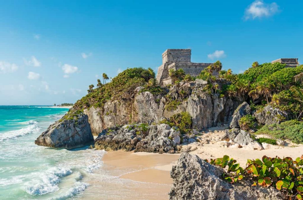 De Mayaruïne van Tulum staat op een rotsachtige kliff met uitzicht op een turquoise zee en wit zandstrand