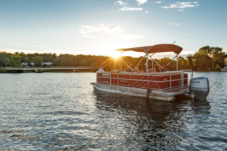 Een groep mensen geniet van een boottocht op een pontonboot op Lake Tuscaloosa terwijl de zon achter de bomen ondergaat
