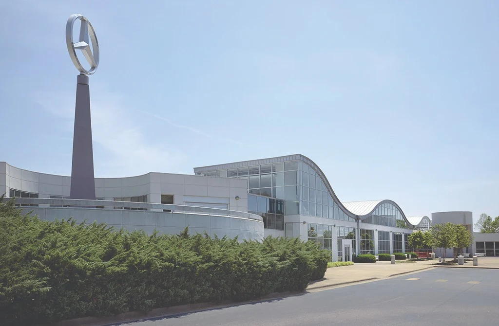Modern golvend gebouw van het Mercedes-Benz Visitor Center in Tuscaloosa met een groot Mercedes-logo op een hoge zuil