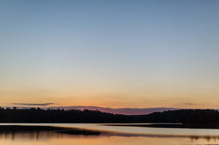Rustige zonsondergang boven het water van Lake Tuscaloosa in Tuscaloosa, met een silhouet van bomen aan de horizon