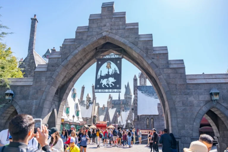 Bezoekers lopen onder een stenen poort met een banier door naar het Harry Potter themagebied van Universal Studios Hollywood