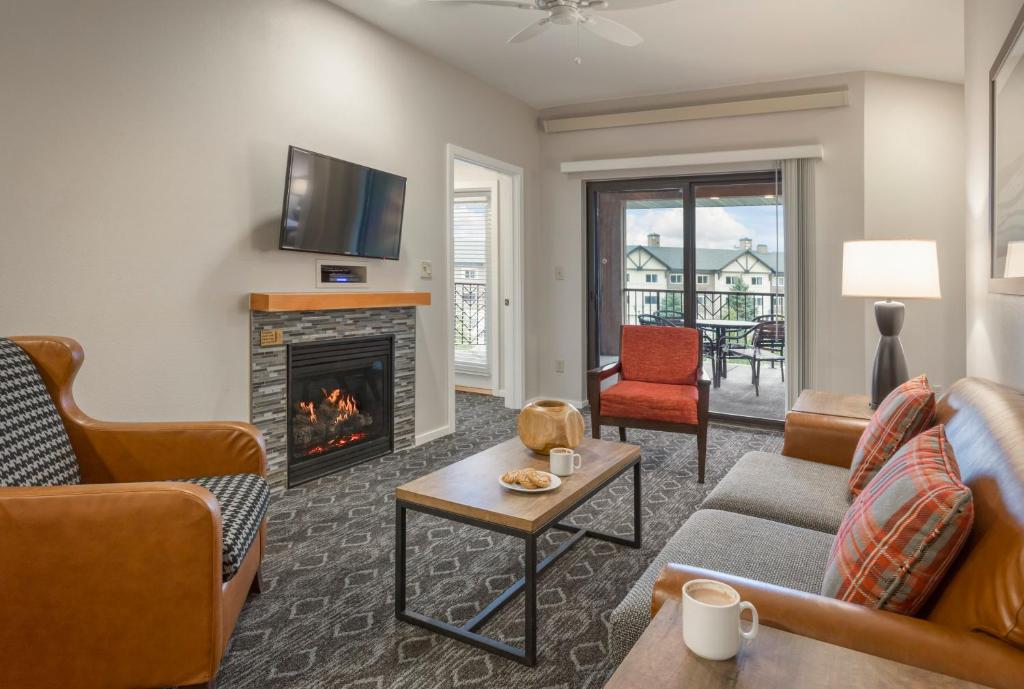 Woonkamer in een vakantieresort met leren fauteuils, een houten salontafel en een openhaard onder een televisie