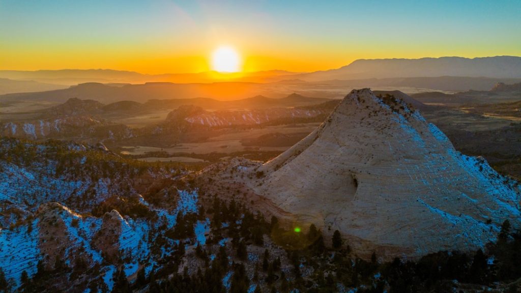 Gouden zonsopkomst boven een landschap van besneeuwde rode rotstoppen en dalen in Utah