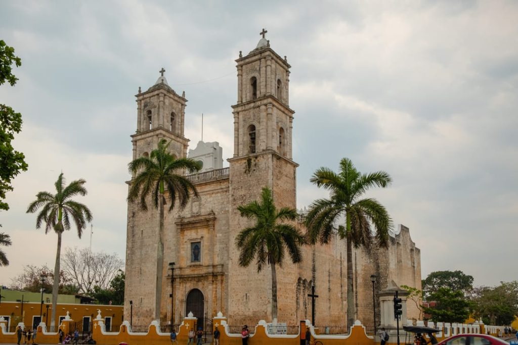 De stenen kathedraal San Servacio met twee torens en palmbomen ervoor onder een grijsbewolkte hemel in Valladolid