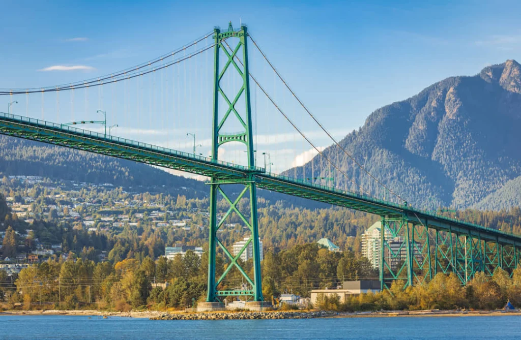 De groene hangbrug Lions Gate Bridge in Vancouver met op de achtergrond bergen en de stad aan het water
