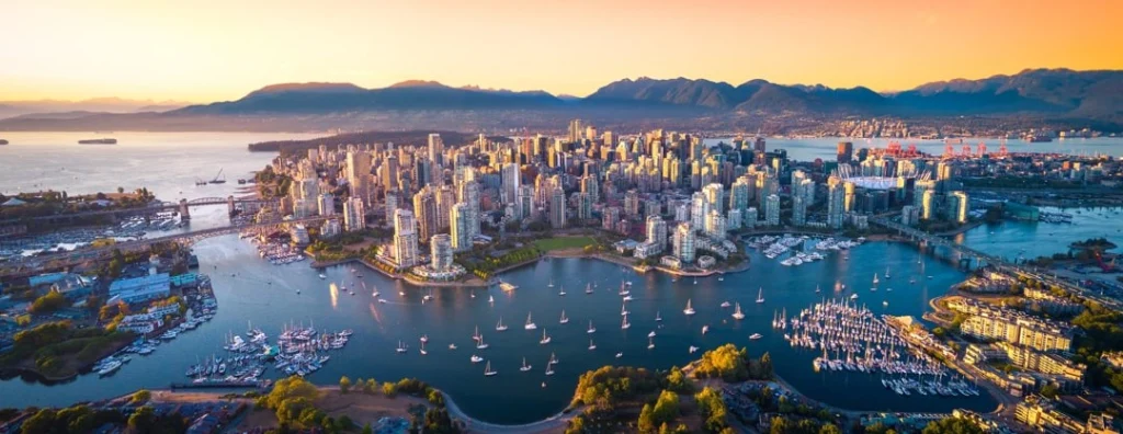 Luchtfoto van de wolkenkrabbers en jachthaven van Vancouver bij zonsondergang, met bergen op de achtergrond