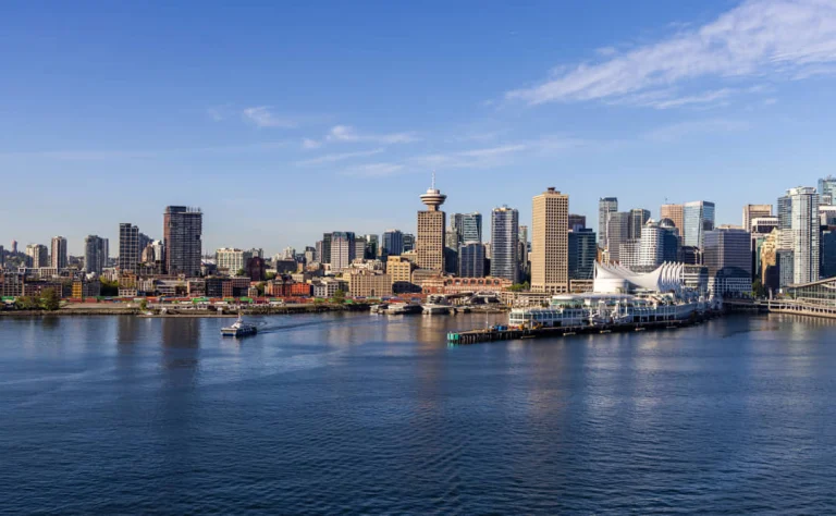 Uitzicht over de haven van Vancouver met wolkenkrabbers, de Harbour Centre toren en Canada Place onder een strakblauwe hemel