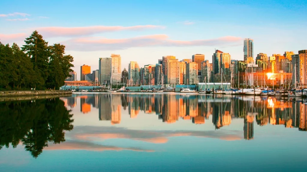 De skyline van Vancouver met wolkenkrabbers en een jachthaven weerspiegelt in kalm water tijdens zonsondergang