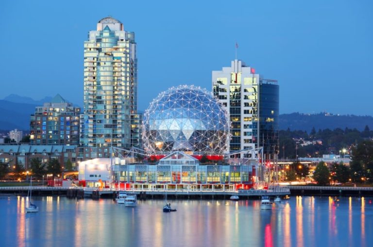 De skyline van Vancouver met de bolvormige koepel van Science World en wolkenkrabbers weerspiegeld in het water tijdens de schemering