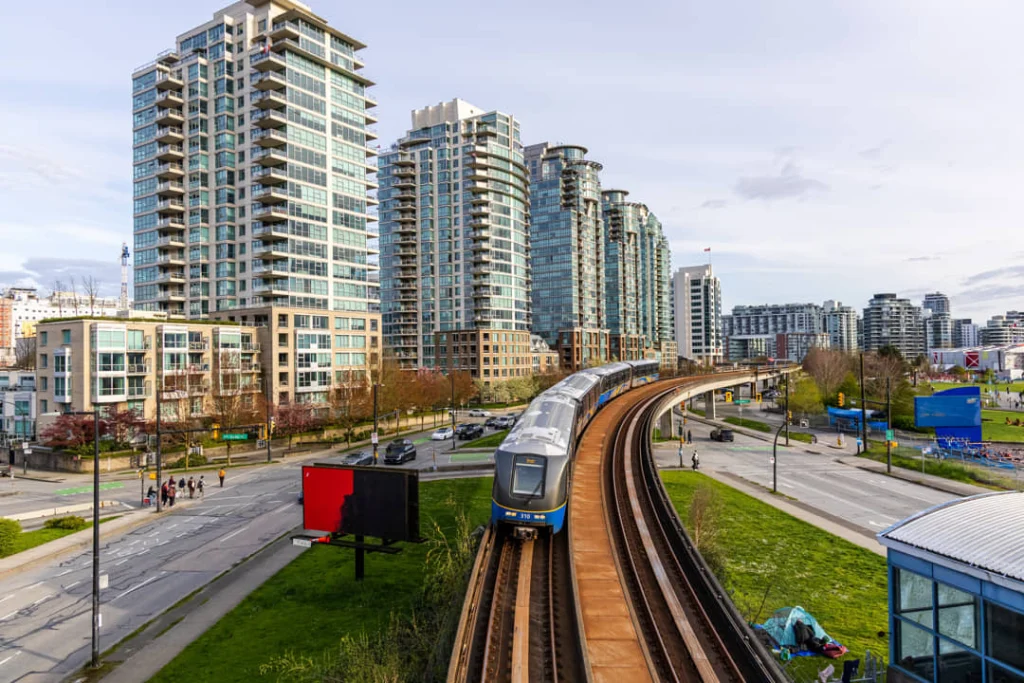 Een skytrain rijdt op verhoogd spoor tussen hoge appartementengebouwen in het centrum van Vancouver